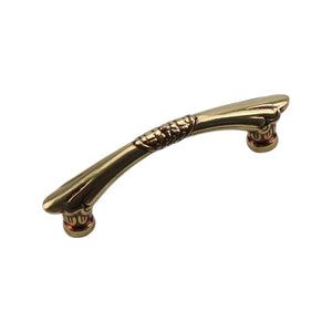 Antique gold-tone curved bar pull with ring bands at the center and tapered ends, 64 mm.