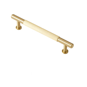 Brushed gold bar pull with a pale textured center grip, 128 mm.