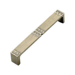 Rectangular bar pull with raised geometric scroll motifs at the center and ends, variant #16, 128 mm.