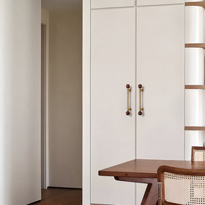 Brass cabinet bar pulls with dark wood ball ends installed on white cabinet doors.
