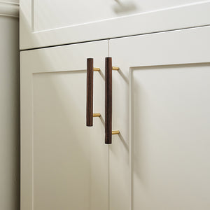 Walnut wood bar cabinet pulls with brass mounts installed on white cabinet doors.