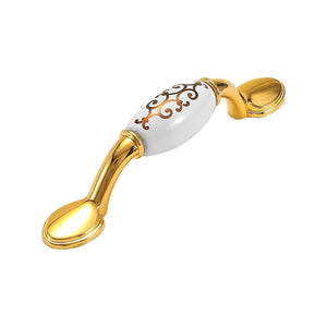 Bar pull with a white scroll-patterned grip and curved gold-tone mounts, option #9, 76 mm.