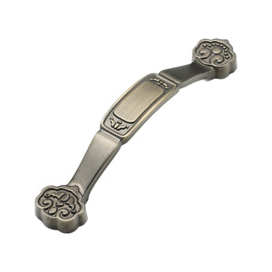 Ornate bridge pull with floral scroll ends and a raised center panel, variant #18, 96 mm.
