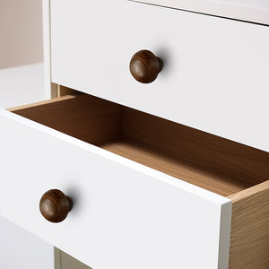 Round walnut wood cabinet knobs fitted to white drawer fronts.