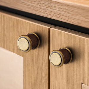 In-use view of cylindrical dark wood cabinet knob with antique bronze brass base and cap, style #14.