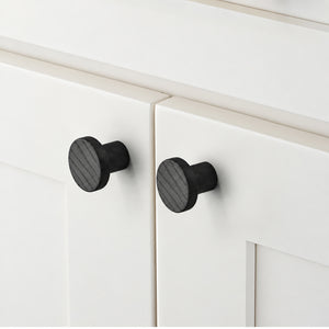 In-use view of flat round black oak cabinet knob, style #2 (33 mm).