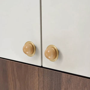 In-use view of light wood half-ball cabinet knob set in a brass cup, style #4.