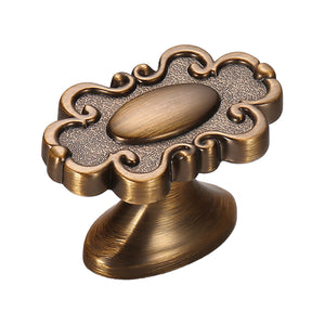 Ornate cabinet knob with a raised oval center and curled outer edge, variant #7.