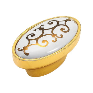 Oval white cabinet knob with a gold-tone scroll pattern, option #2.