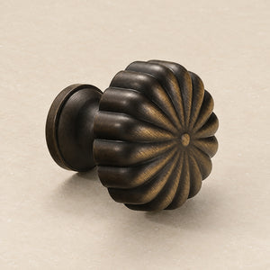 Fluted flower-shaped bronze-finish brass cabinet knob from the side.