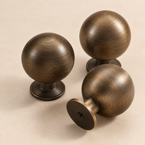 Three spherical bronze-finish brass cabinet knobs from front and side angles.