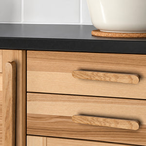 Oak wood cabinet finger pulls installed on cabinetry.