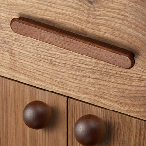 In-use view of slim rounded reddish wood finger pull, 96 mm option.