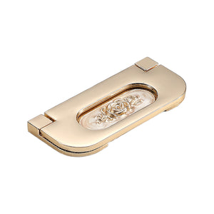 Gold-tone folding pull with an oval recessed panel and raised rose detail, option #3.