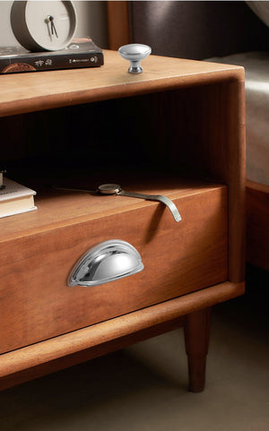 Solid brass open-back cup pull in Polished Chrome shown on the drawer of a bedside table.