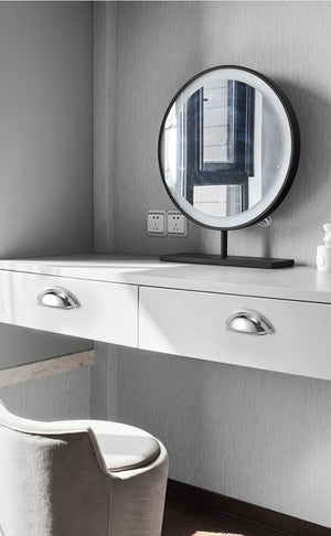 Solid brass open-back cup pulls in Polished Chrome shown on white vanity drawers beneath a round mirror.