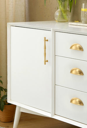 Solid brass open-back cup pulls in Satin Brass on white sideboard drawers.