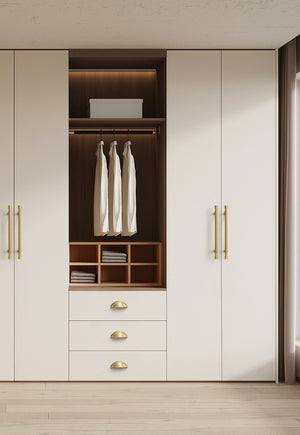Solid brass open-back cup pulls in Satin Brass on the drawers of a white wardrobe.