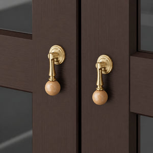In-use view of light wood ball drop pull with a brass stem and round base, style #5.