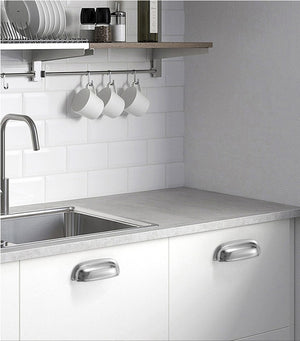 Solid brass rounded dome cup pulls in Polished Chrome on white kitchen cabinets beneath a sink.