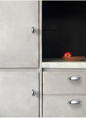 Solid brass smooth half-moon cup pulls in Polished Chrome on light-colored kitchen drawers.