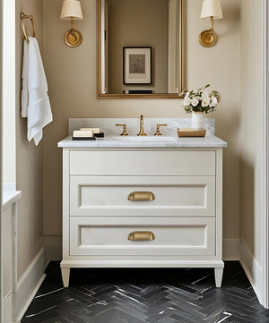 Solid brass soft-corner cup pulls in Aged Brass on the drawers of a white bathroom vanity.