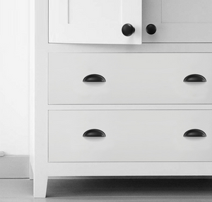Four matte black half-moon cup pulls on two white dresser drawers.