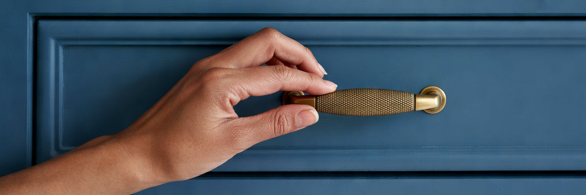 Hand touching knurled brass cabinet pull