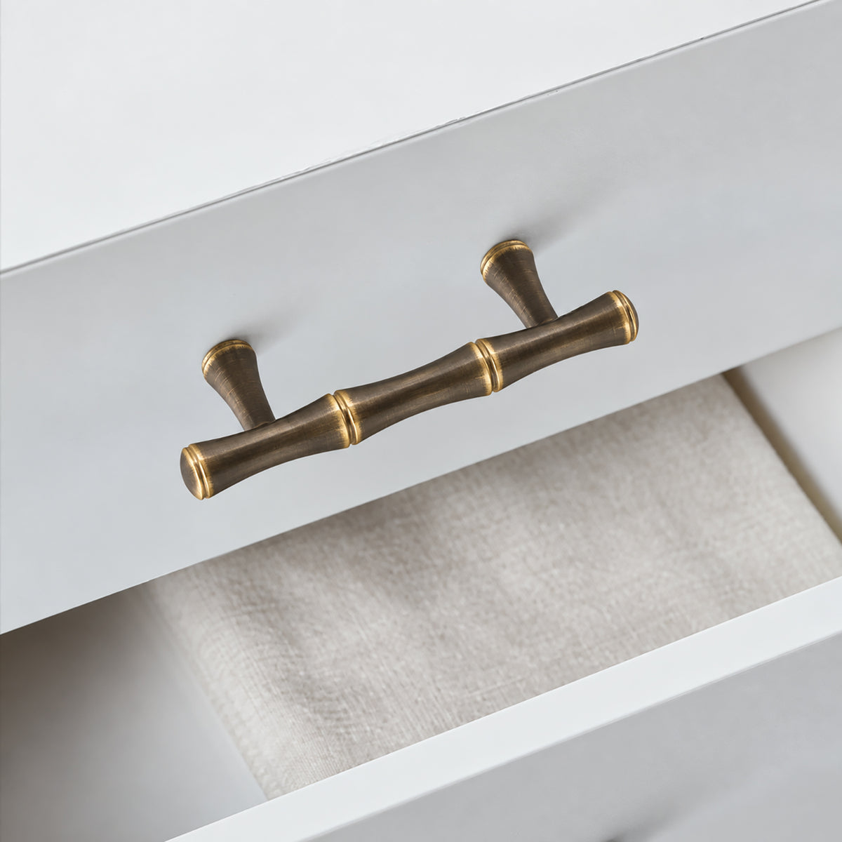 In-use view of segmented dark antique brass bar cabinet pull with gold rings, style #11 (64 mm).