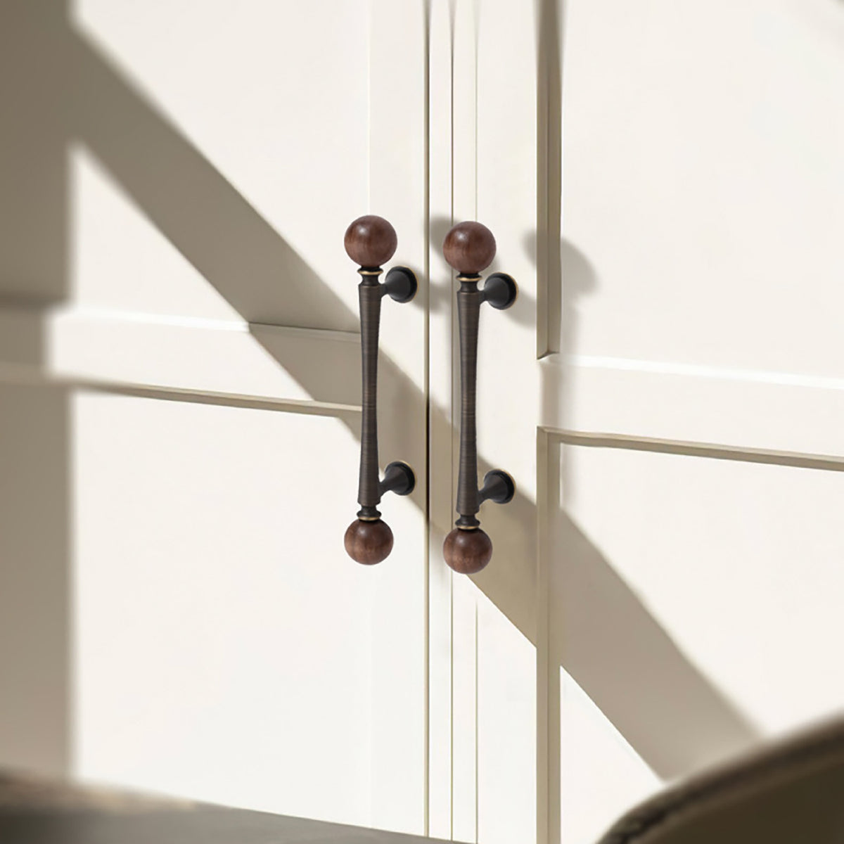 In-use view of dark antique brass bar cabinet pull with wood ball ends, style #3 (96 mm).