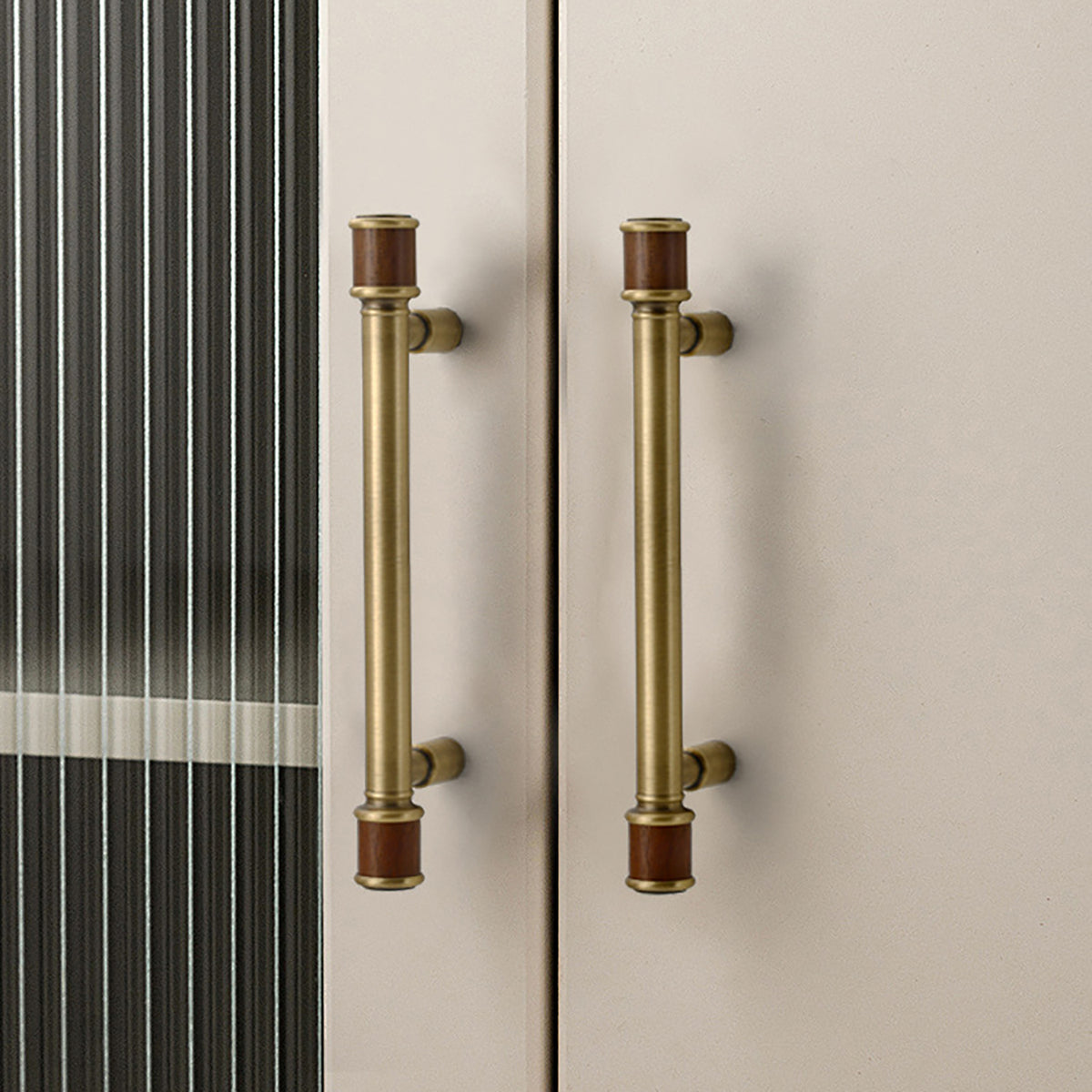 Brass bar cabinet pulls with dark wood end sleeves installed on tall cabinet doors.