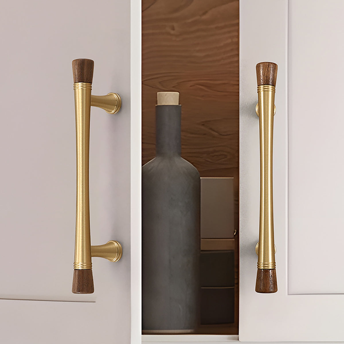 Brass cabinet bar pull with dark wood ends installed on a white cabinet door.
