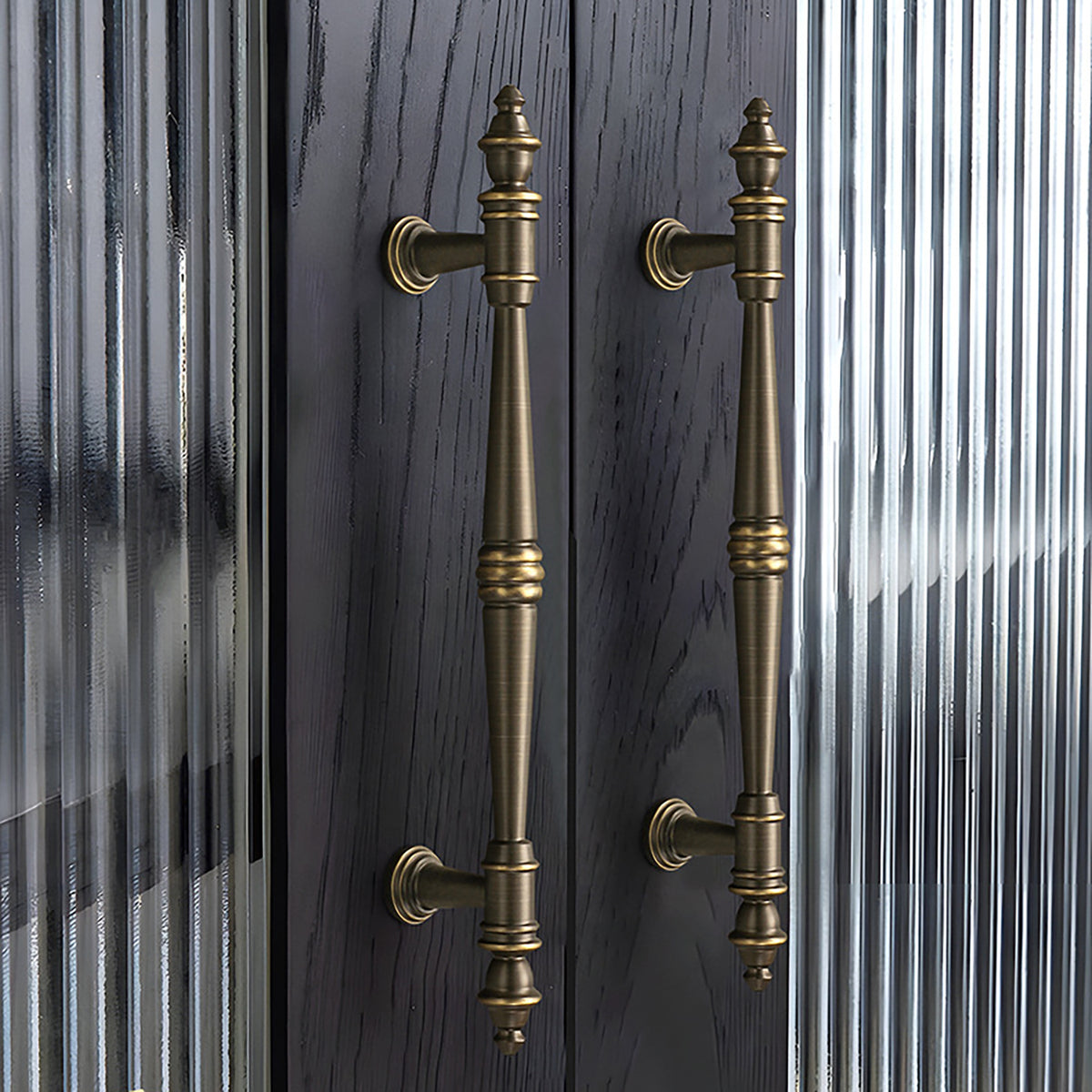 Ornate dark antique brass bar pulls installed on dark wood cabinet doors.
