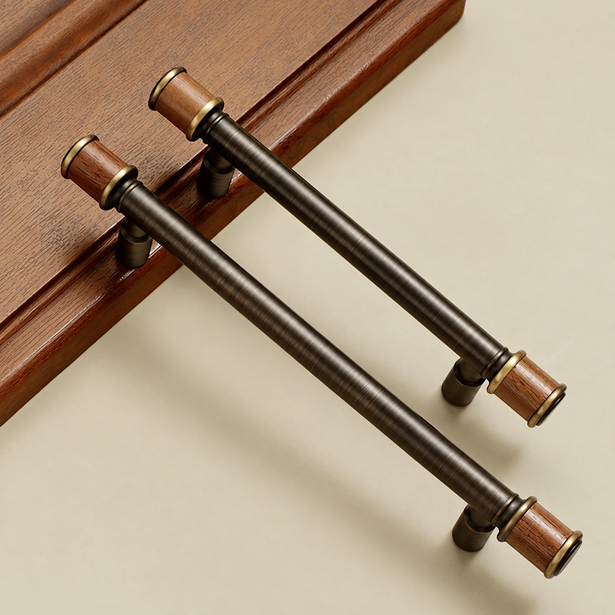 Two dark antique brass bar pulls with brown end caps, shown on a wooden surface.