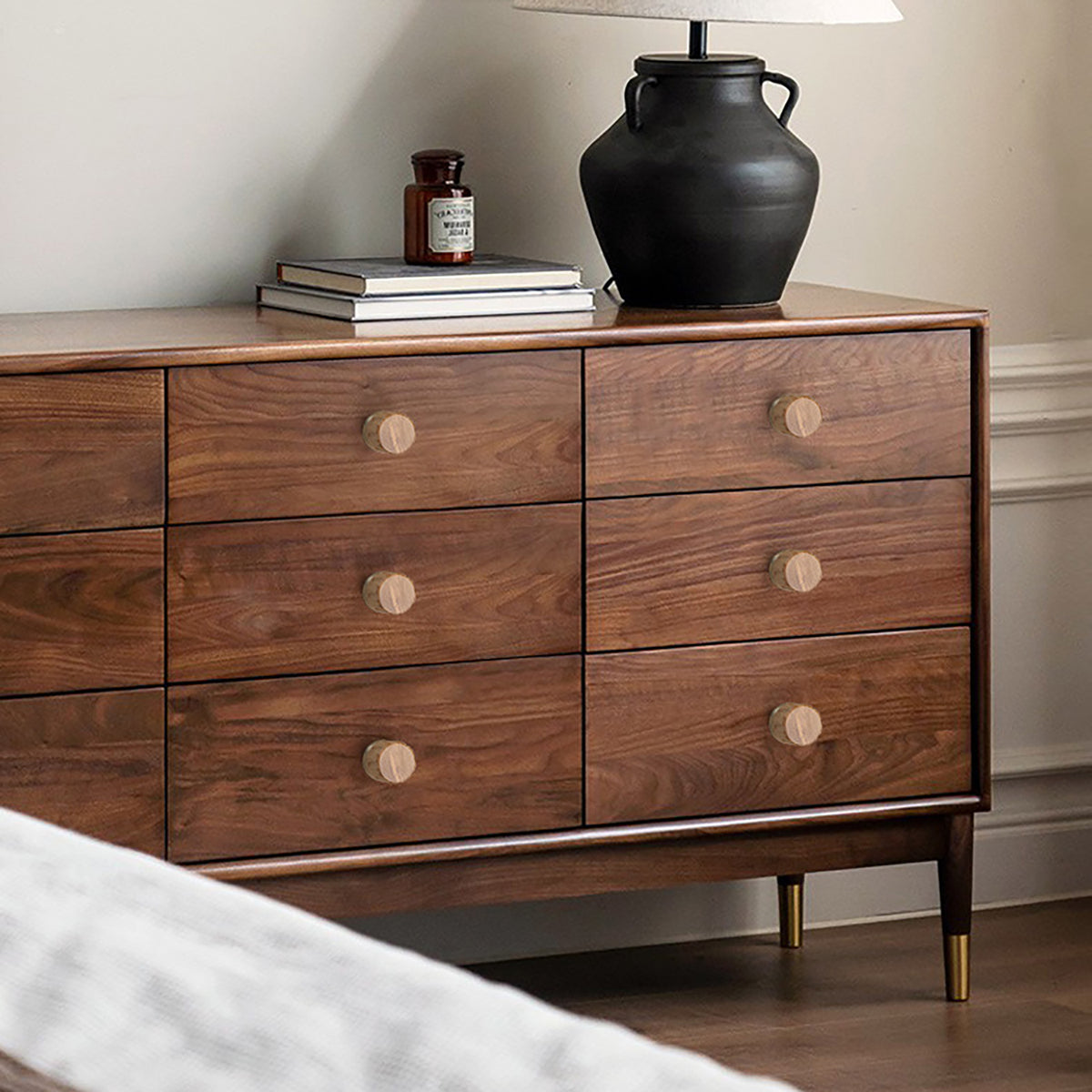 Oak wood cabinet knobs with brass bases fitted to the drawers of a walnut dresser.