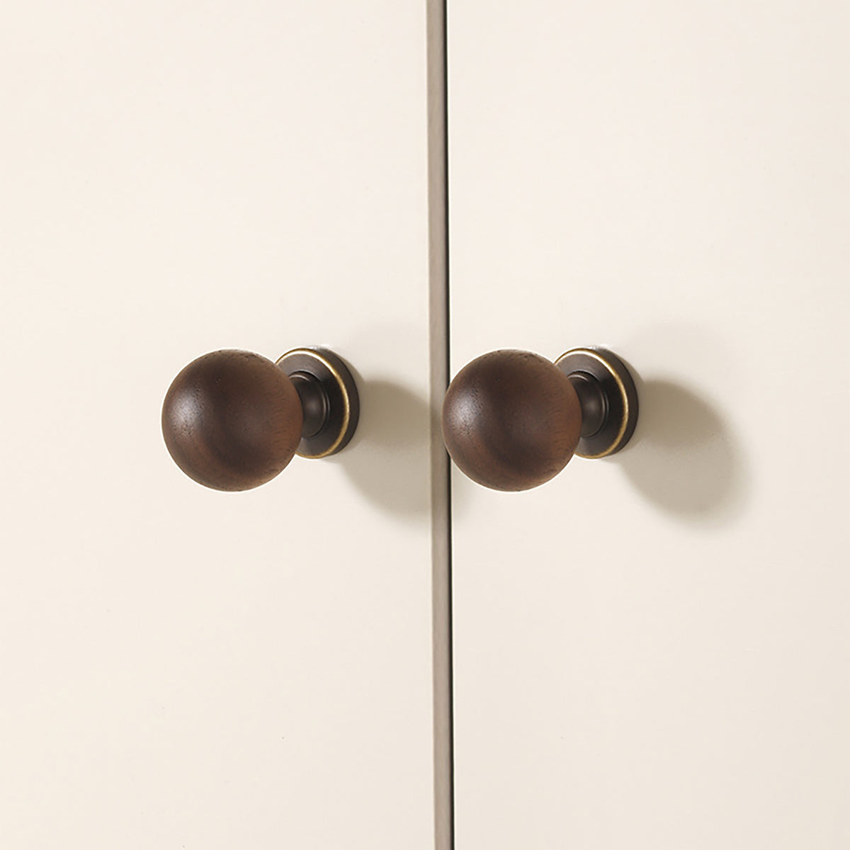 In-use view of dark wood ball cabinet knob with antique bronze brass base, style #10 (30 mm).