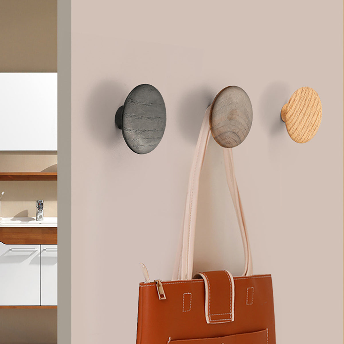 Black oak oval cabinet knob shown with beech and walnut knobs used as wall hooks.