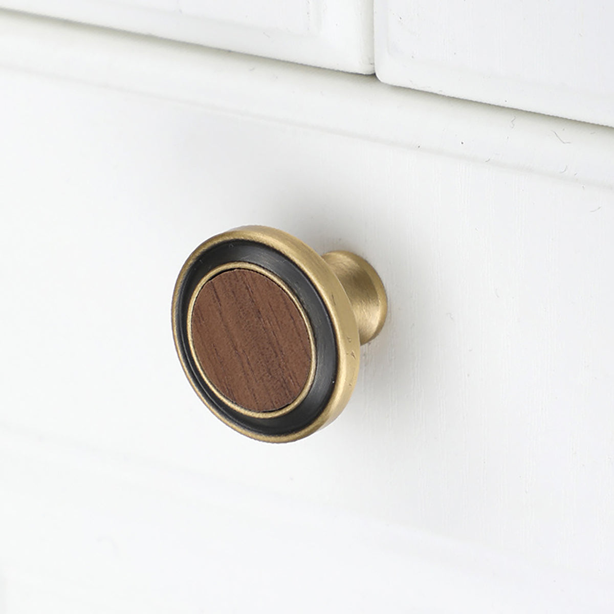 In-use view of flat round brass cabinet knob with dark wood inset, style #16 (22 mm).