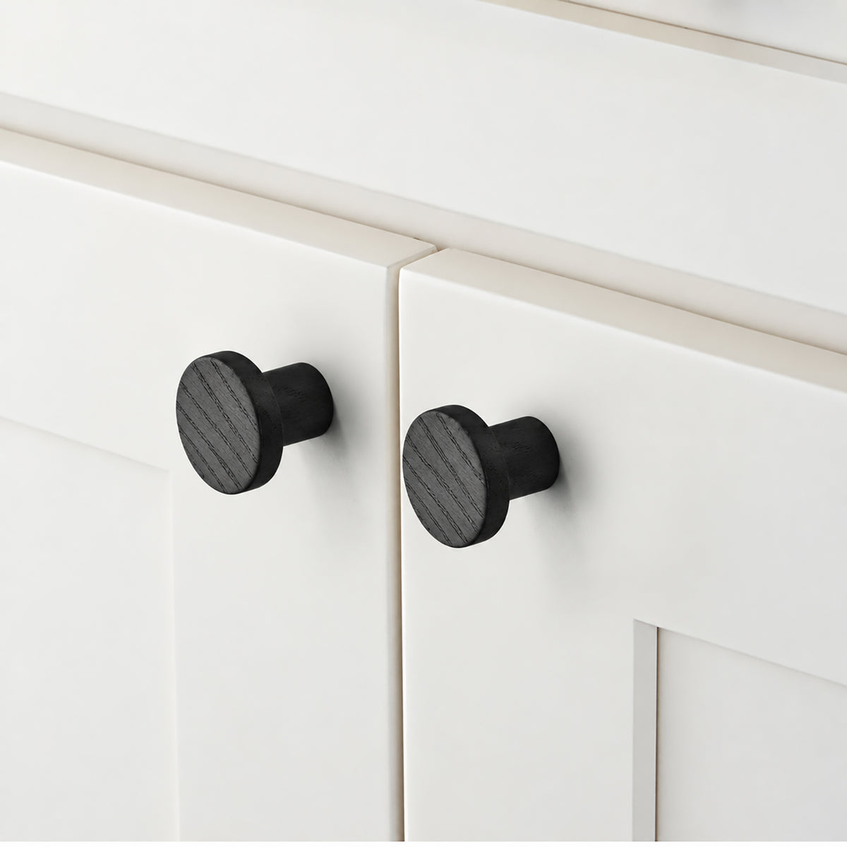 In-use view of flat round black oak cabinet knob, style #2 (33 mm).