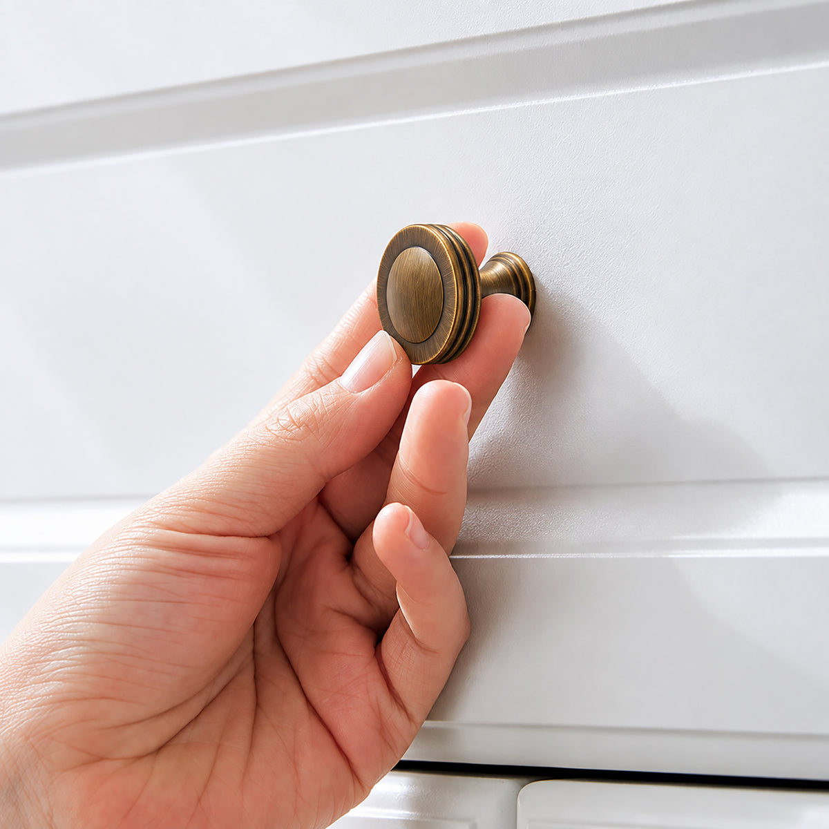 In-use view of ringed concave antique bronze brass cabinet knob, style #22.