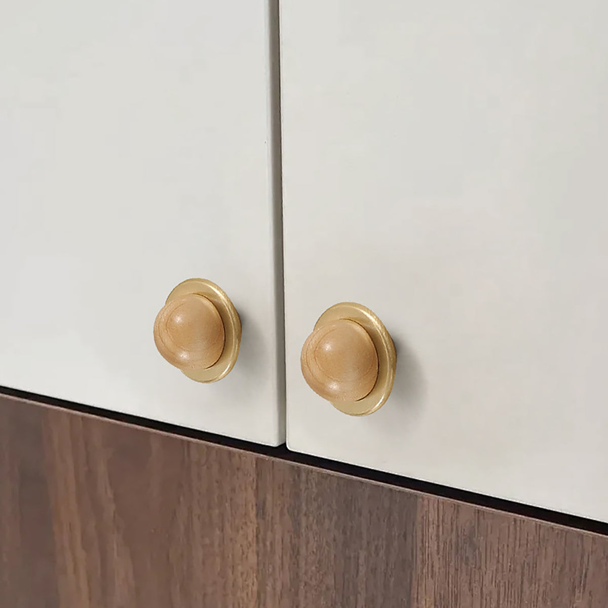 In-use view of light wood half-ball cabinet knob set in a brass cup, style #4.