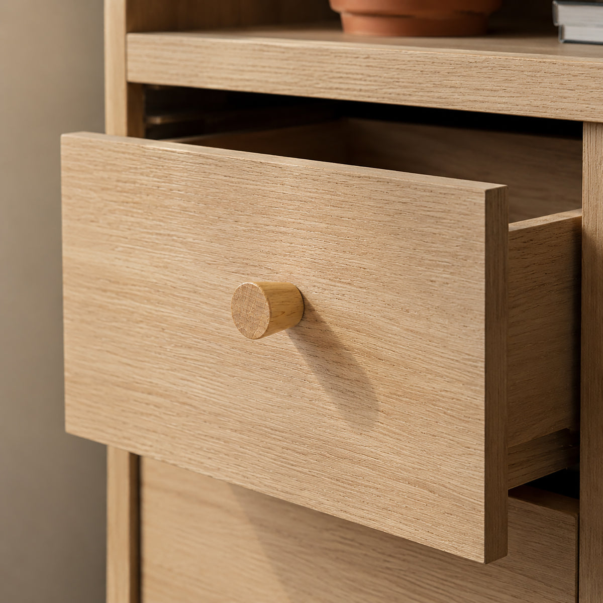 In-use view of light wood cabinet knob with a tapered neck and flat top, style #4.