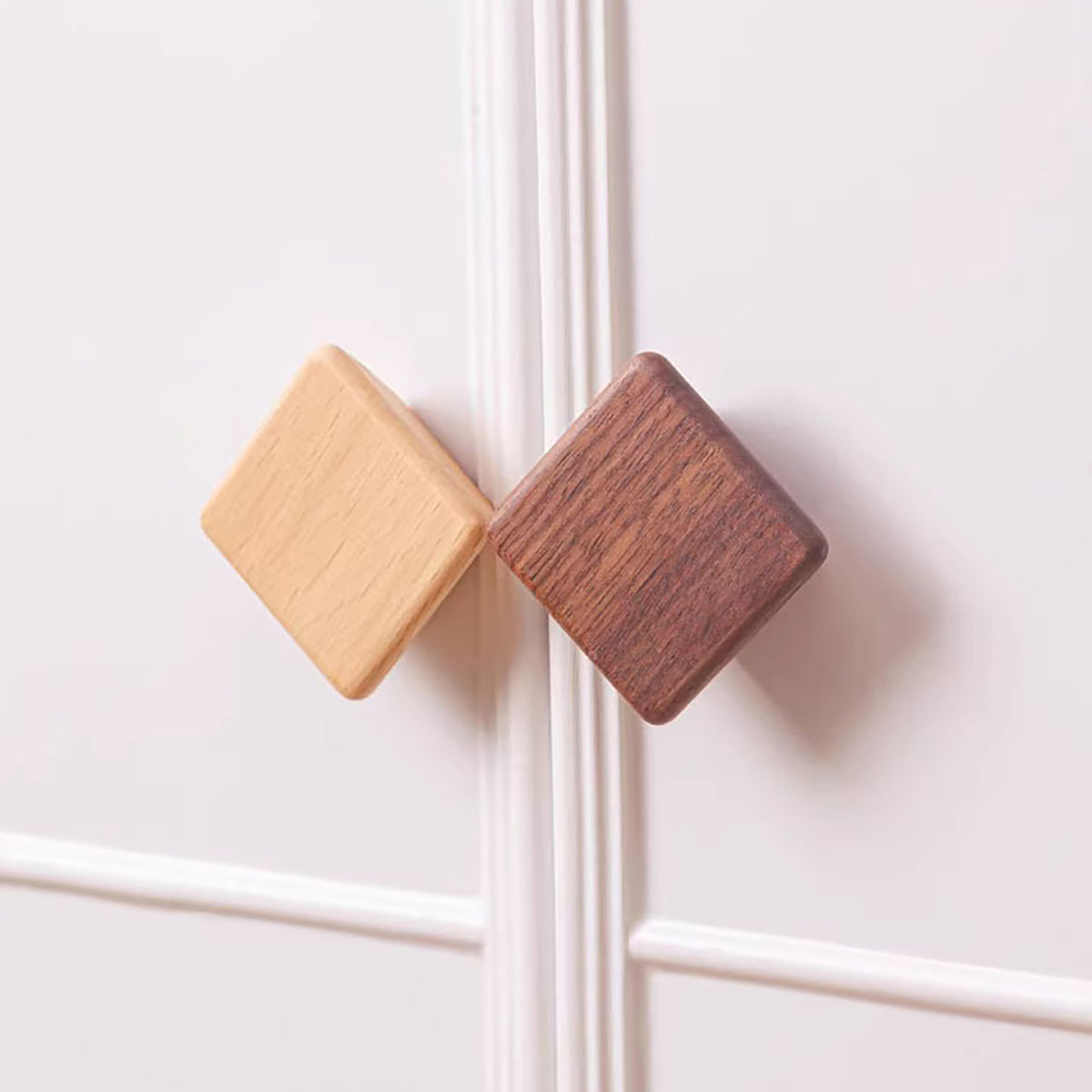 Beech and walnut square wood cabinet knobs fitted to white cabinet doors.