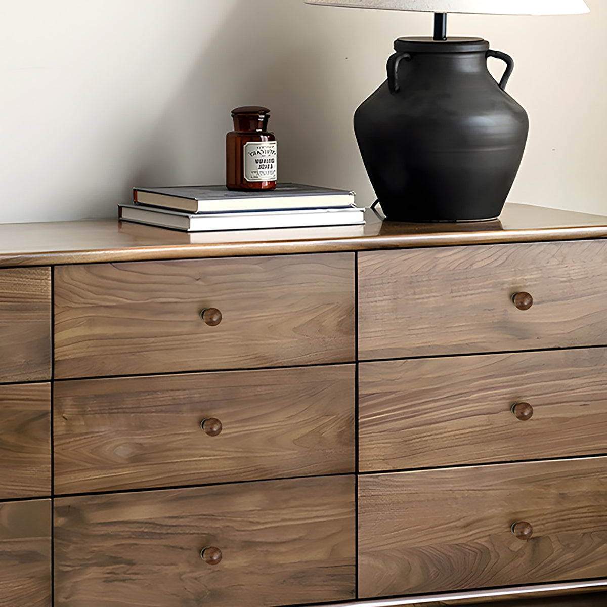 Small round cabinet knobs on a walnut dresser in a styled bedroom.