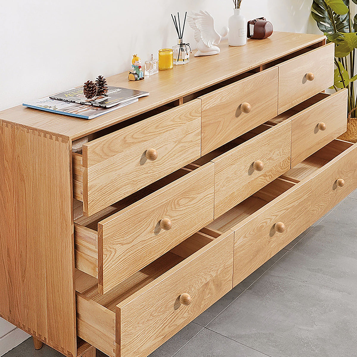 Light wood cabinet knobs installed on an open chest of drawers.