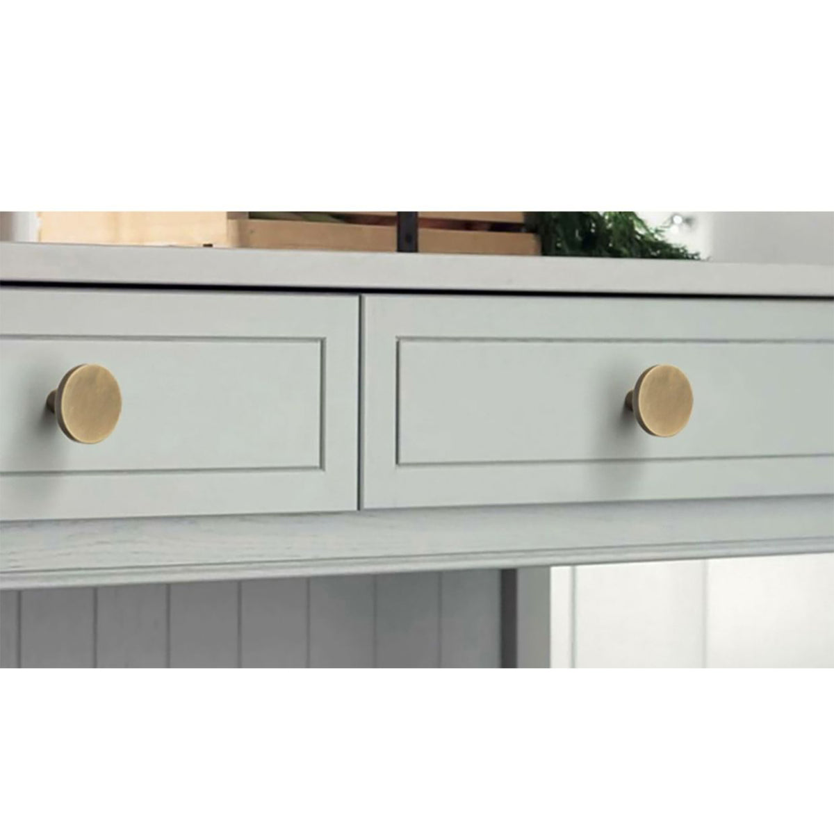 Round brass cabinet knobs installed on pale gray drawers.