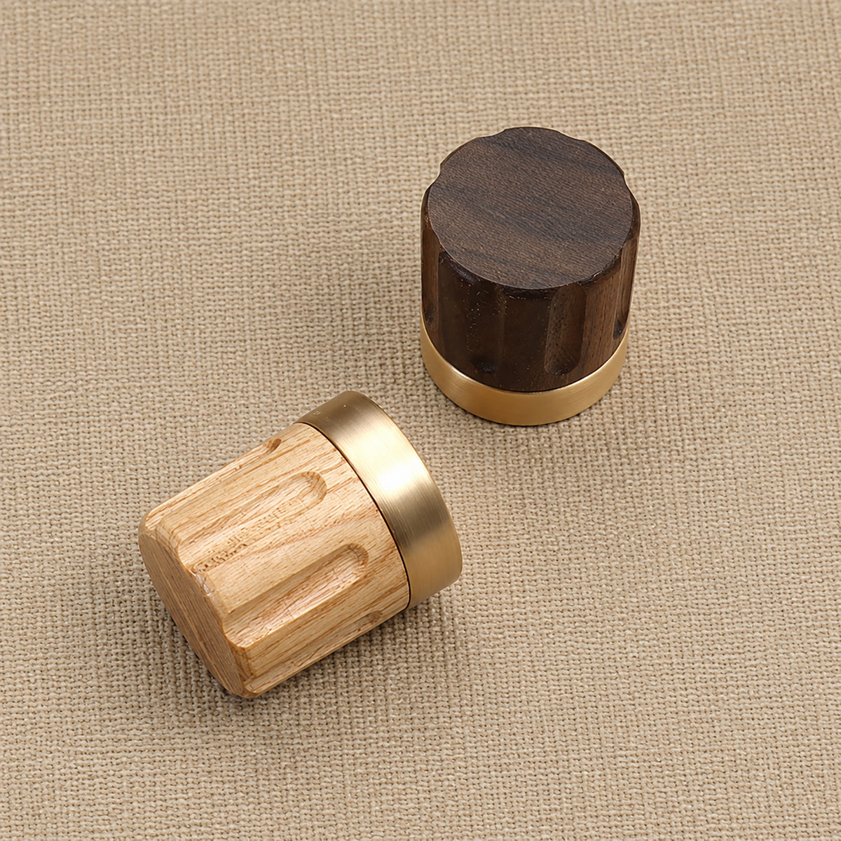 Oak and walnut fluted wood cabinet knobs with brass bases on woven fabric.