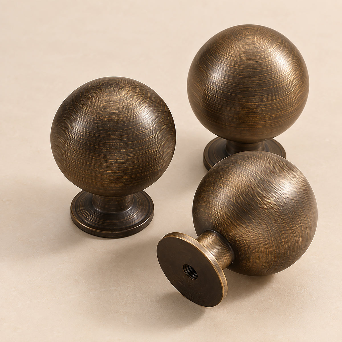 Three spherical bronze-finish brass cabinet knobs from front and side angles.