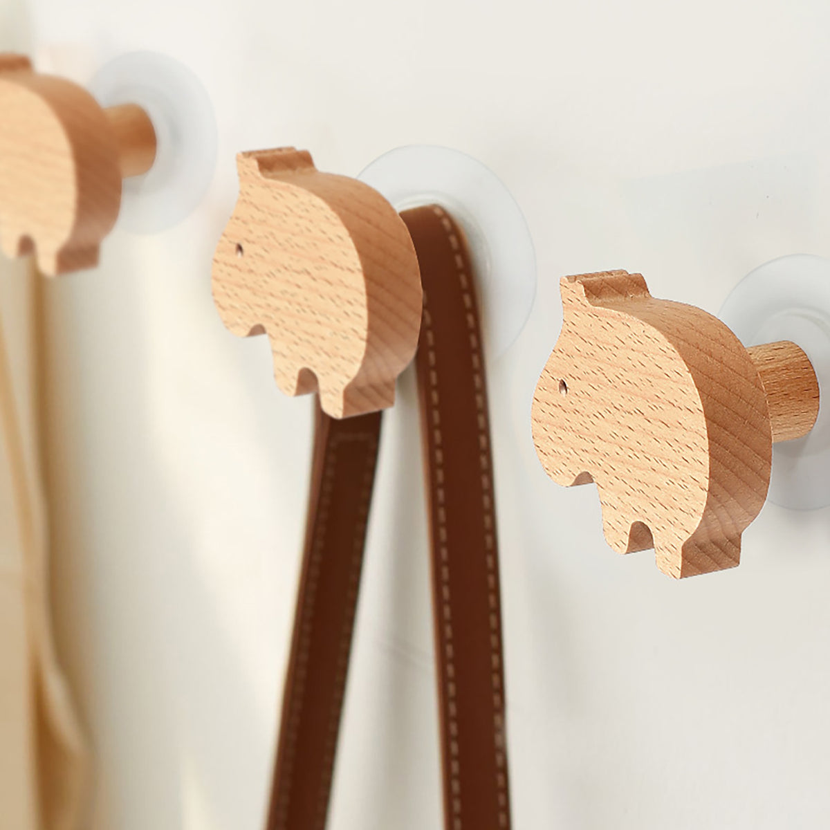 Capybara-shaped wood wall hooks holding straps.