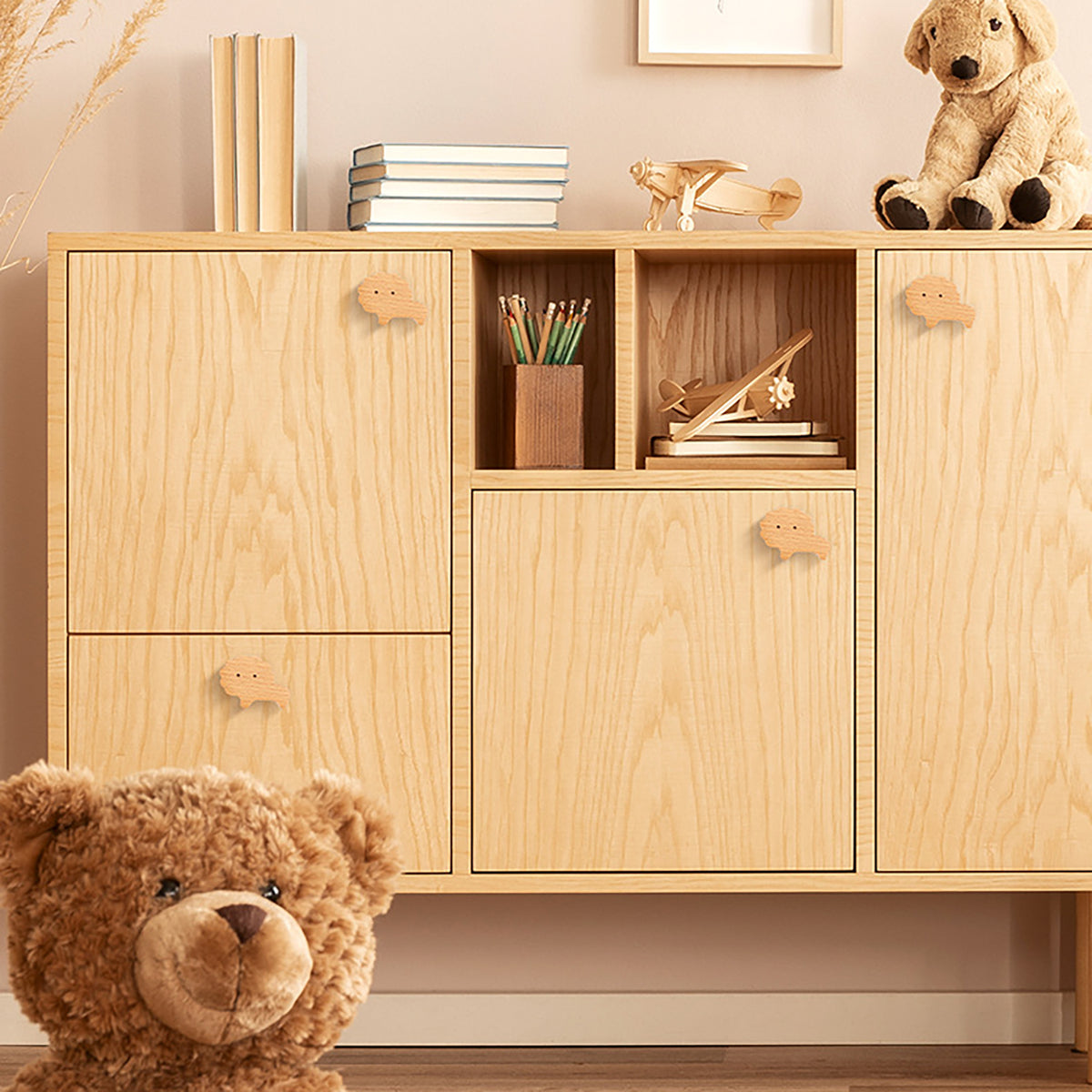 Lion-shaped wood knobs on a light-wood storage cabinet.